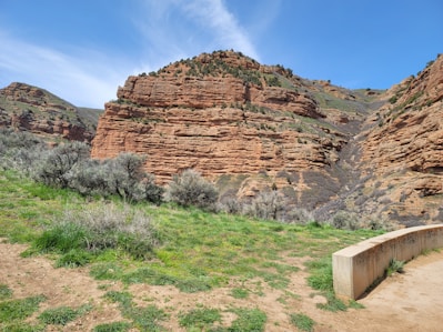 A rugged red rock wall forming the exterior of a modern home under a clear blue sky