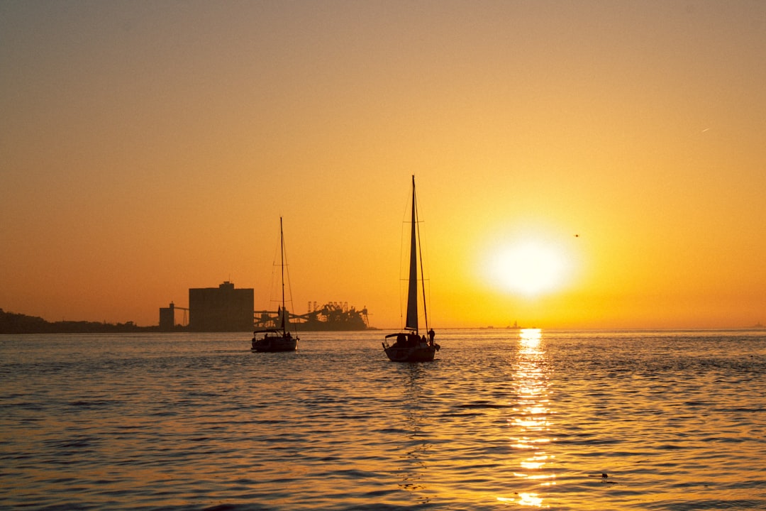 a couple of boats floating on top of a body of water, Atardecer en el Rio Tajo, Lisboa, Portugal.