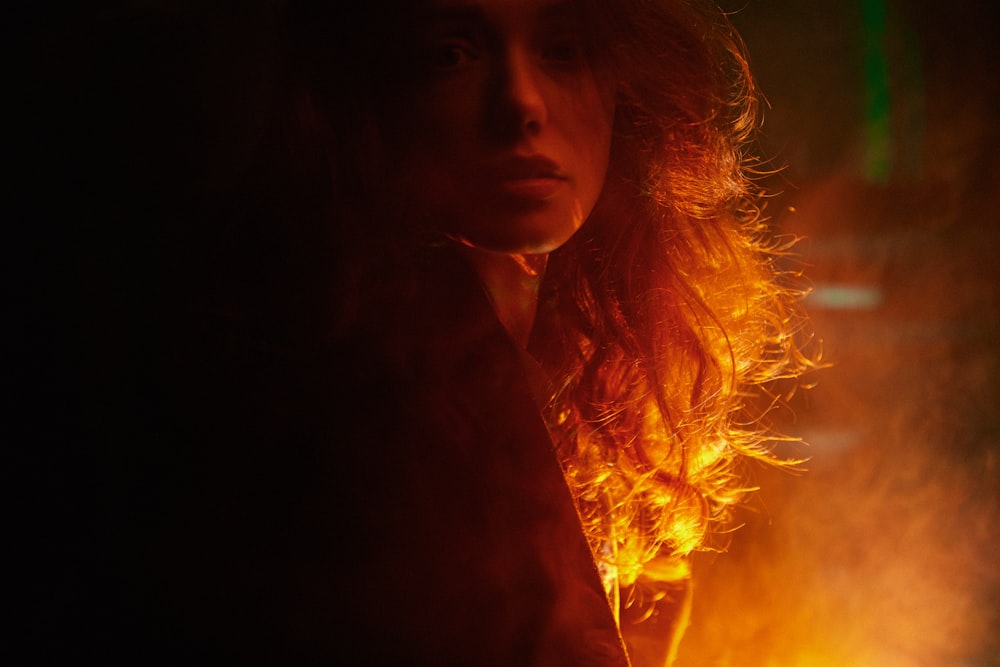 a woman with long hair standing in front of a fire