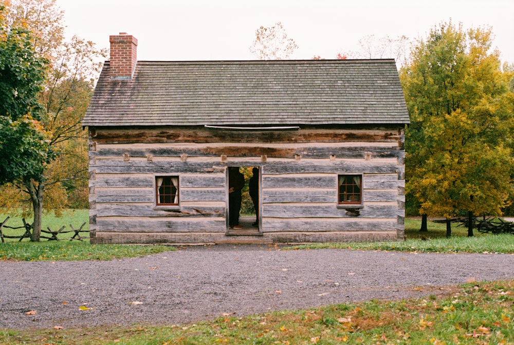 an old log cabin sits in the middle of a field