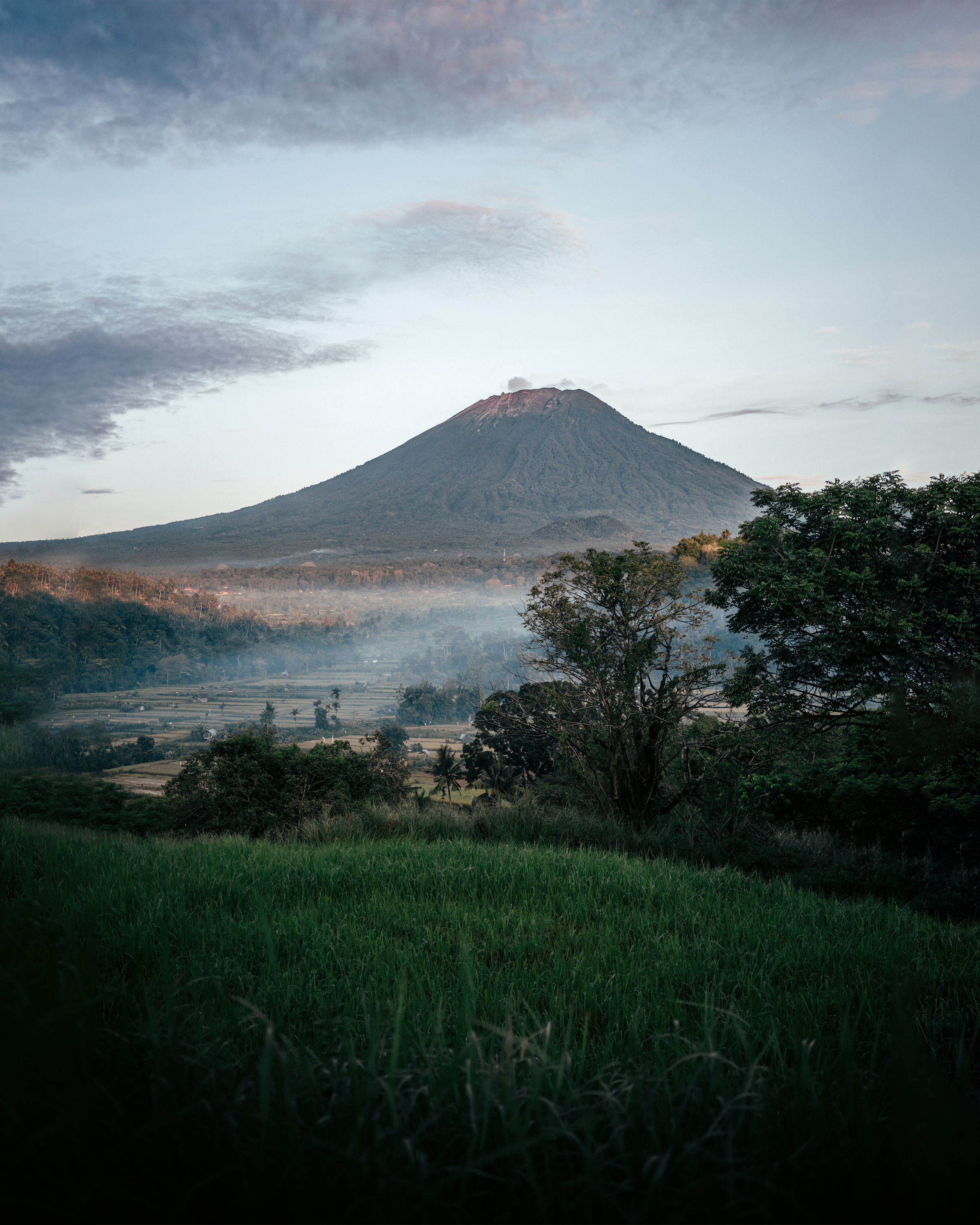 A cinematic sunrise view of Arenal Volcano with mist swirling in the surrounding rainforest.