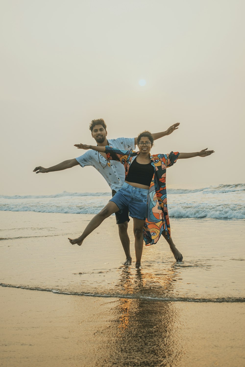 um par de pessoas que estão de pé na areia