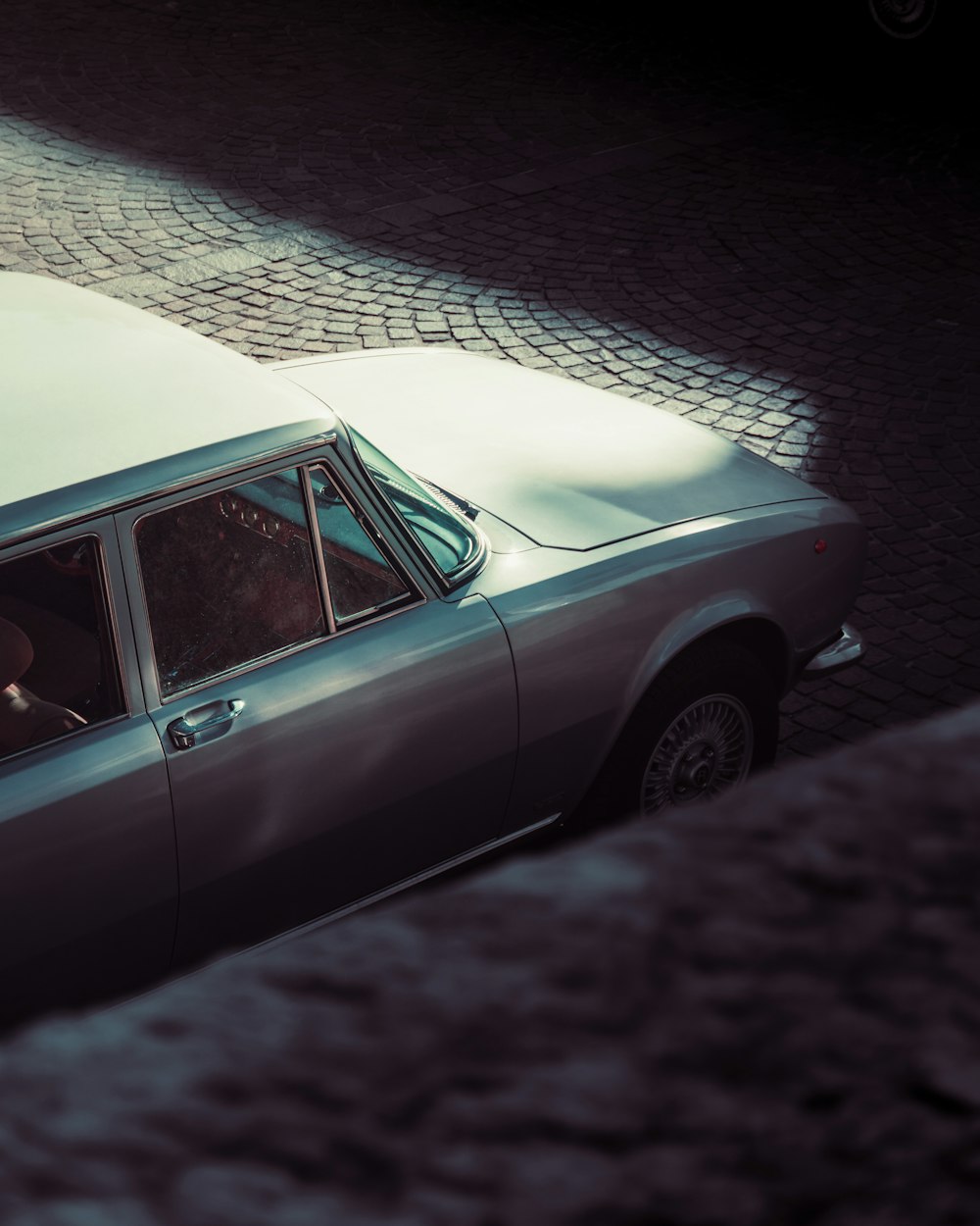 a silver car parked on a cobblestone street