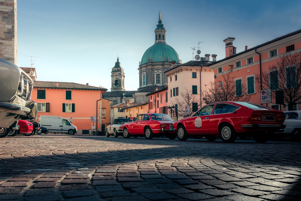 a red car is parked on a cobblestone street