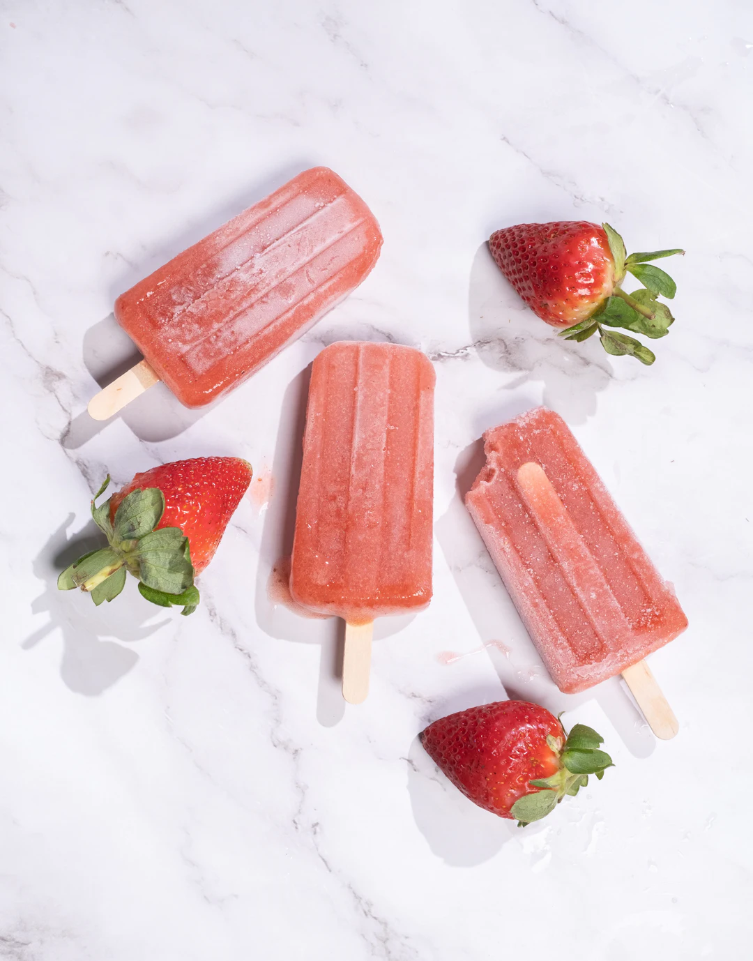 Strawberry popsicles on a marble counter