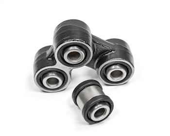 A close-up of metal mechanical components consisting of multiple rubber bushings. The bushings are primarily black with a metallic silver inner ring and are set against a plain white background.