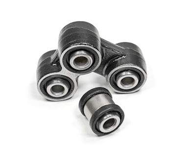 A close-up of metal mechanical components consisting of multiple rubber bushings. The bushings are primarily black with a metallic silver inner ring and are set against a plain white background.