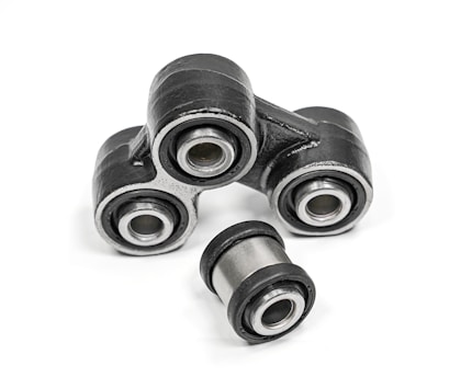 A close-up of metal mechanical components consisting of multiple rubber bushings. The bushings are primarily black with a metallic silver inner ring and are set against a plain white background.
