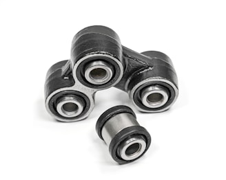A close-up of metal mechanical components consisting of multiple rubber bushings. The bushings are primarily black with a metallic silver inner ring and are set against a plain white background.