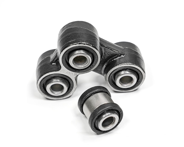 A close-up of metal mechanical components consisting of multiple rubber bushings. The bushings are primarily black with a metallic silver inner ring and are set against a plain white background.