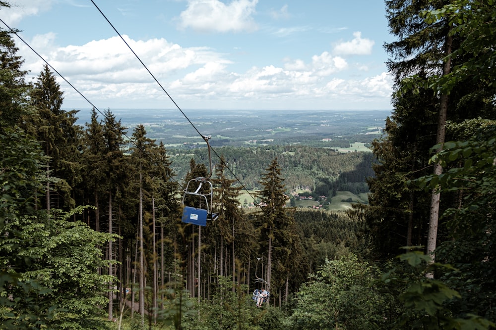 a person riding a ski lift in the middle of a forest