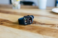 A stylish smartwatch displaying fitness stats, set against a casual outfit on a wooden table.