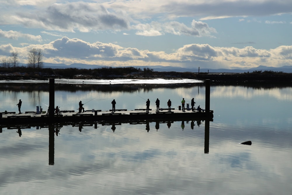 a group of people standing on a pier next to a body of water