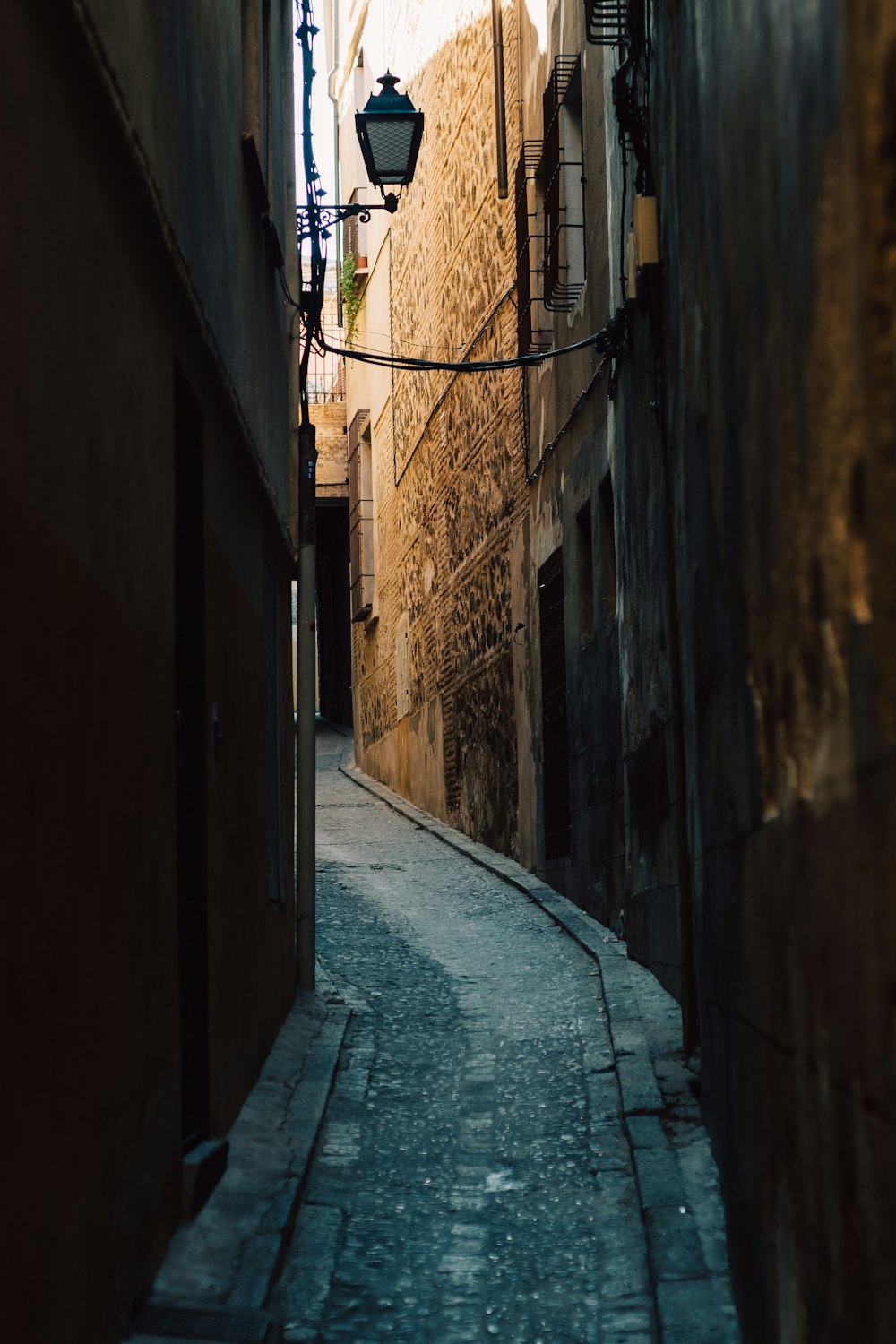 a narrow alley way with a lamp on the side