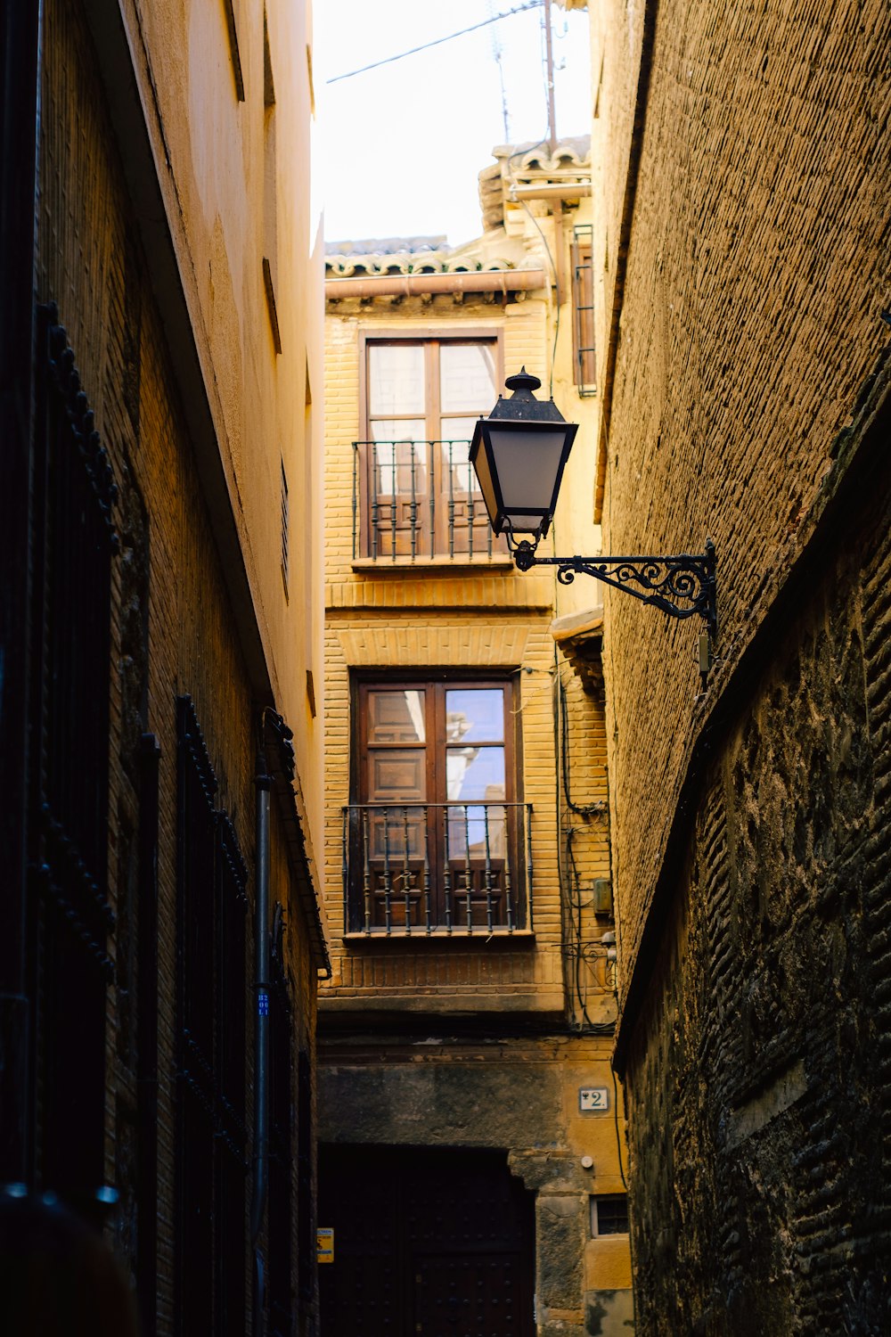 a narrow alley way with a light hanging from the side