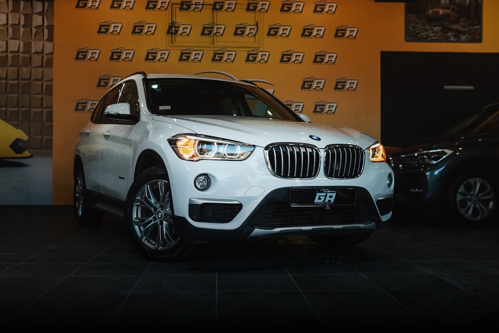 a white bmw suv parked in front of a wall