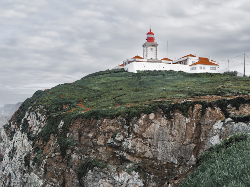 a white and red lighthouse on top of a cliff