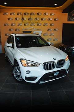 A sleek white 2020 BMW X5 parked in front of a modern home with deep red accent lighting.