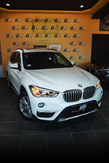 A shiny white BMW displayed in a modern showroom with bright lighting.
