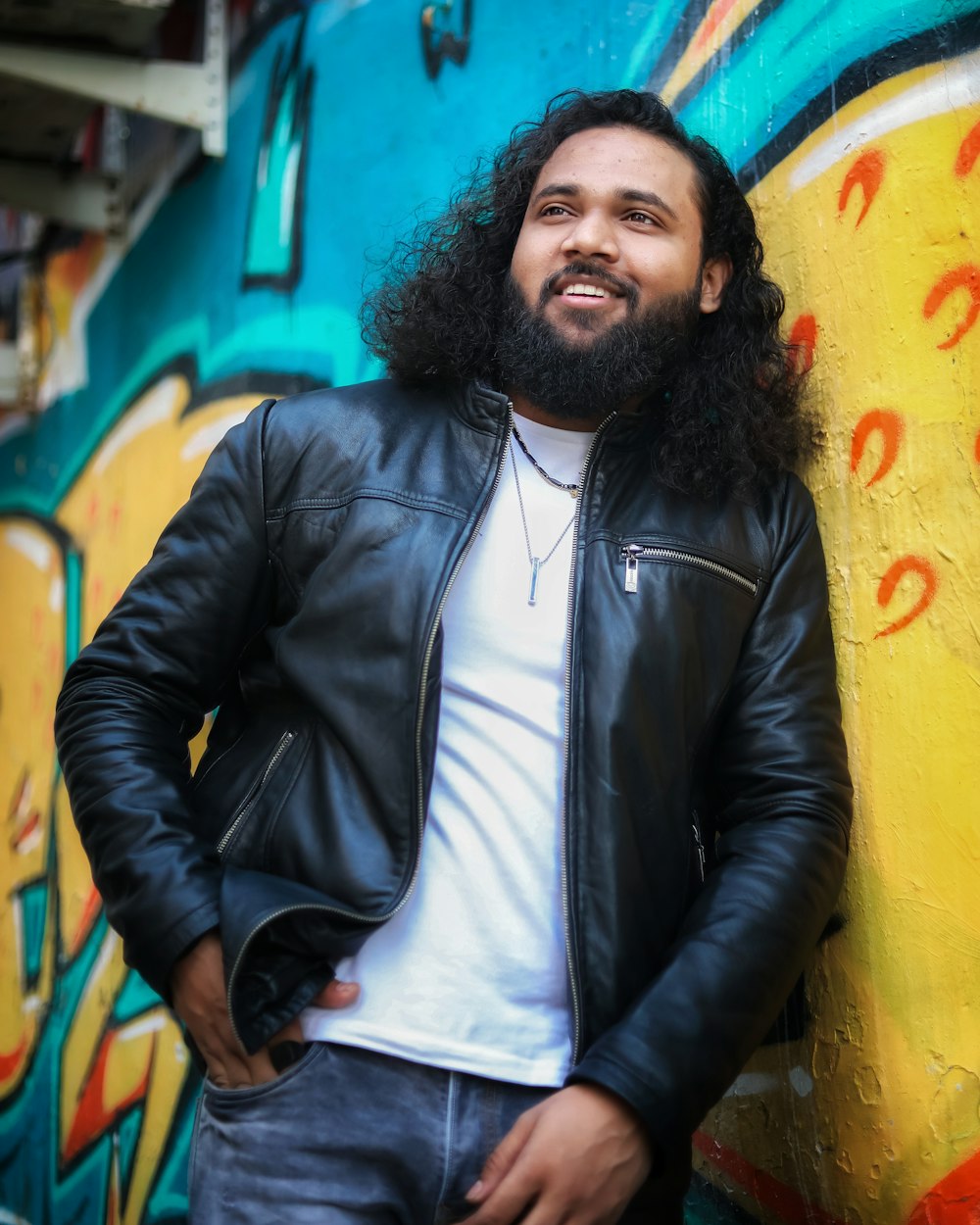 a man with a beard standing next to a wall