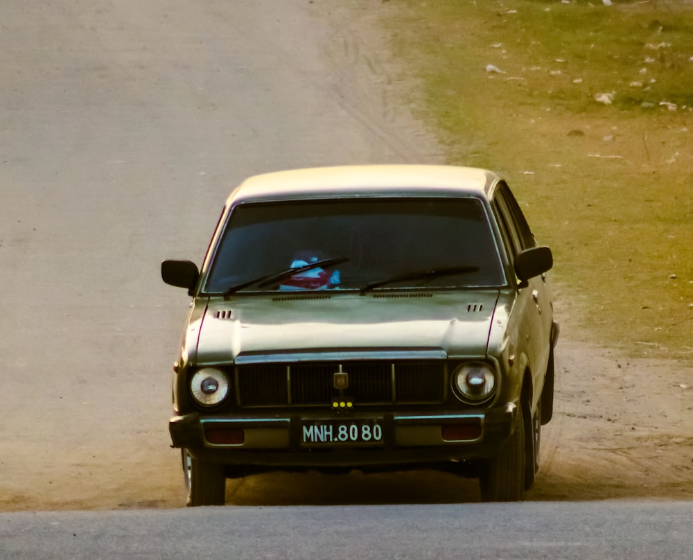 a white car driving down a dirt road