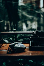 Close-up of hands dialing a classic fax machine with a blurred background of early telecom equipment.