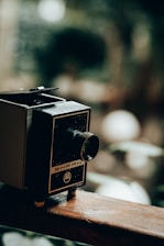A vintage film reel resting on an aged wooden table with golden light highlighting its texture.