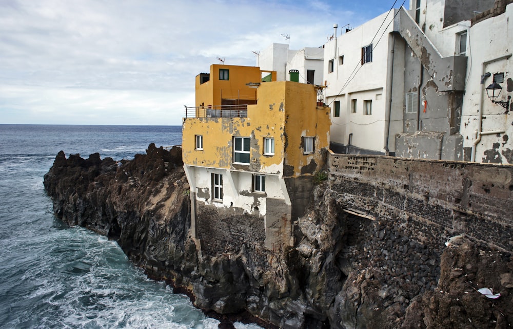 a house on the edge of a cliff next to the ocean