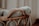 A textured, knit blanket is draped over the edge of a wicker basket. The scene is softly lit, creating a warm and cozy atmosphere.