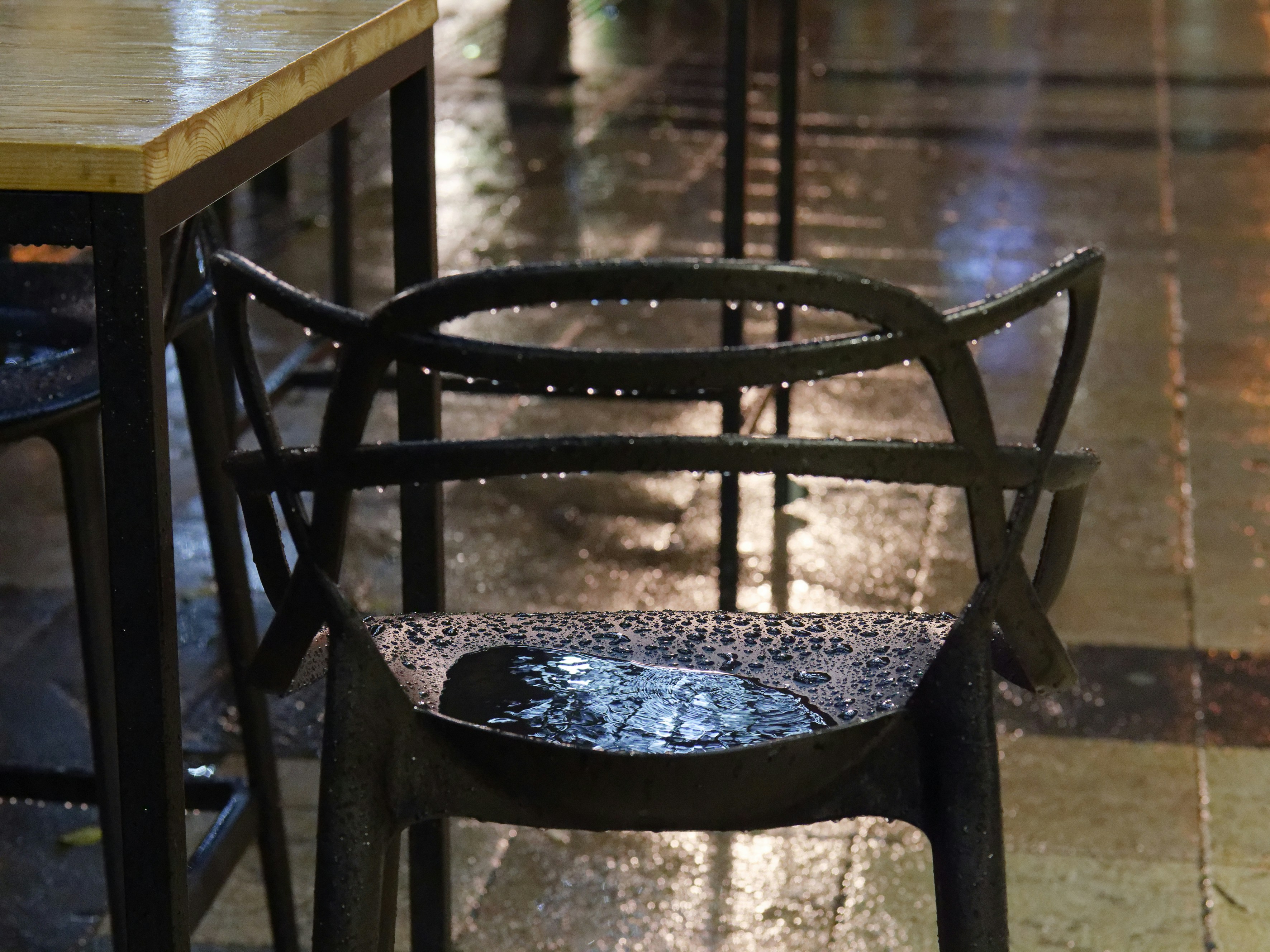 a table and a chair sitting on a wet sidewalk