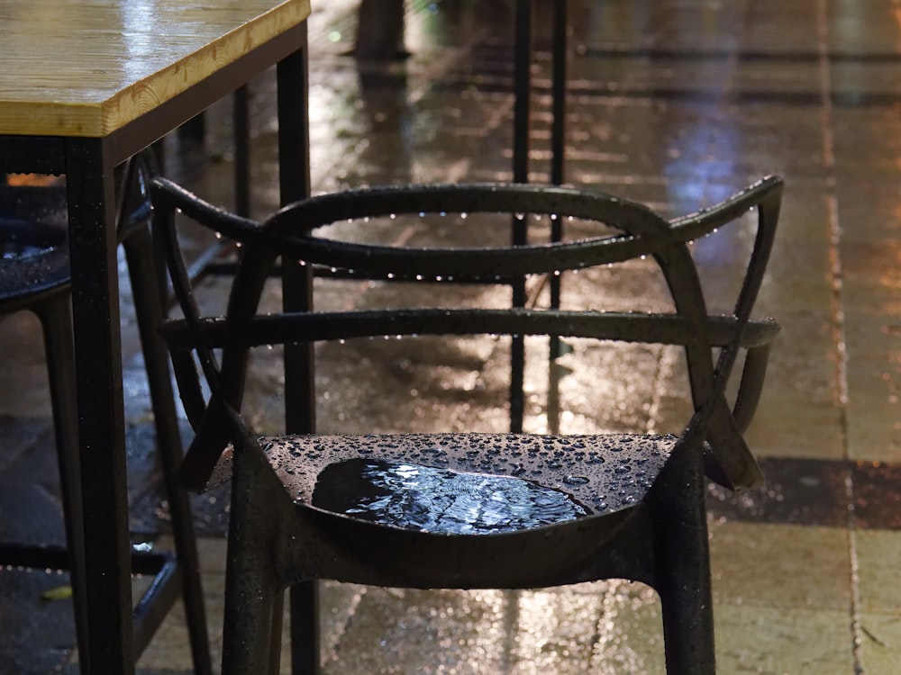 a table and a chair sitting on a wet sidewalk
