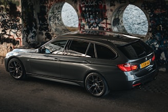 A sleek black van parked outside a modern train station in the Weppes region.