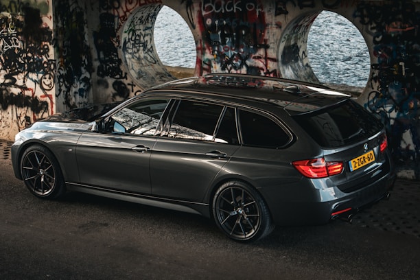 A sleek black van parked outside a modern train station in the Weppes region.