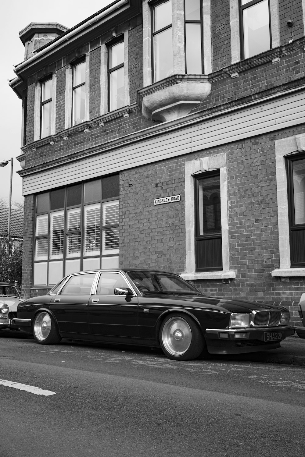 a black and white photo of a car parked in front of a building