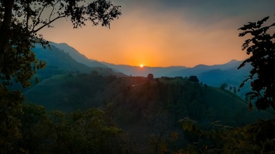 Golden sun setting behind rolling hills and a winding river in West Virginia.
