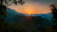 Sunset over lush green hills and the Gulf of Nicoya from a cozy farm cabin.