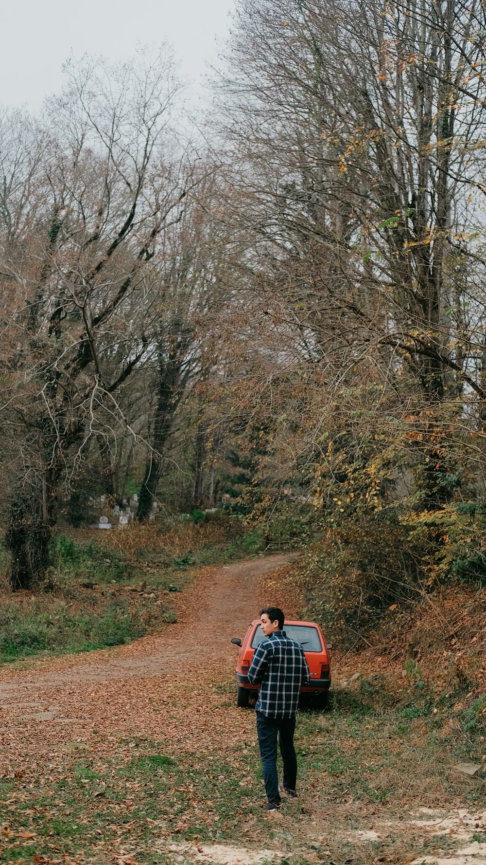 a man walking down a dirt road next to a forest