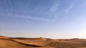 Vast desert dunes under a clear blue sky in Central Asia, inviting peaceful solitude.