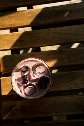 Minimalist shot of a purple-hued açaí smoothie in a clear glass with condensation droplets.