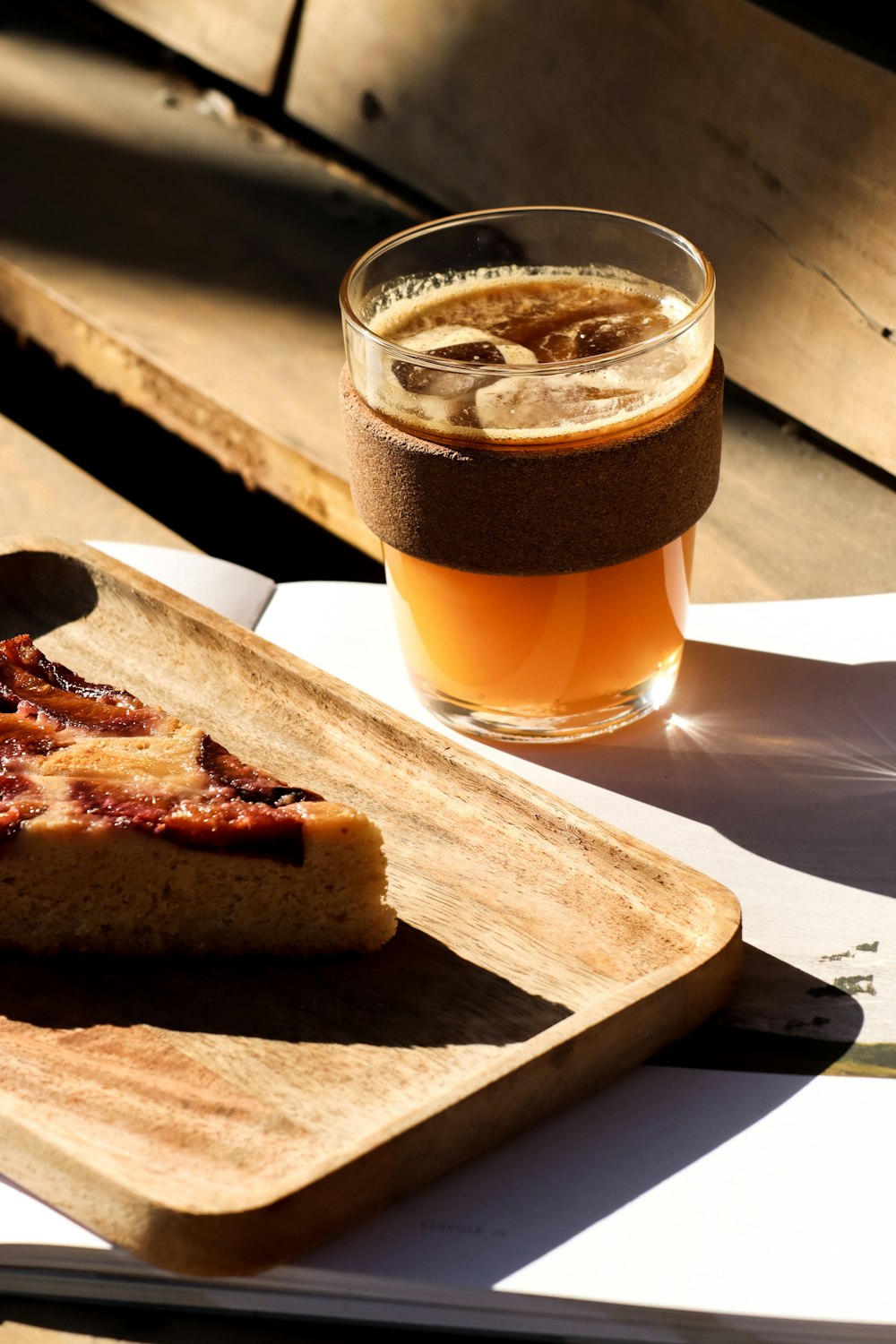 a piece of pizza on a cutting board next to a glass of beer