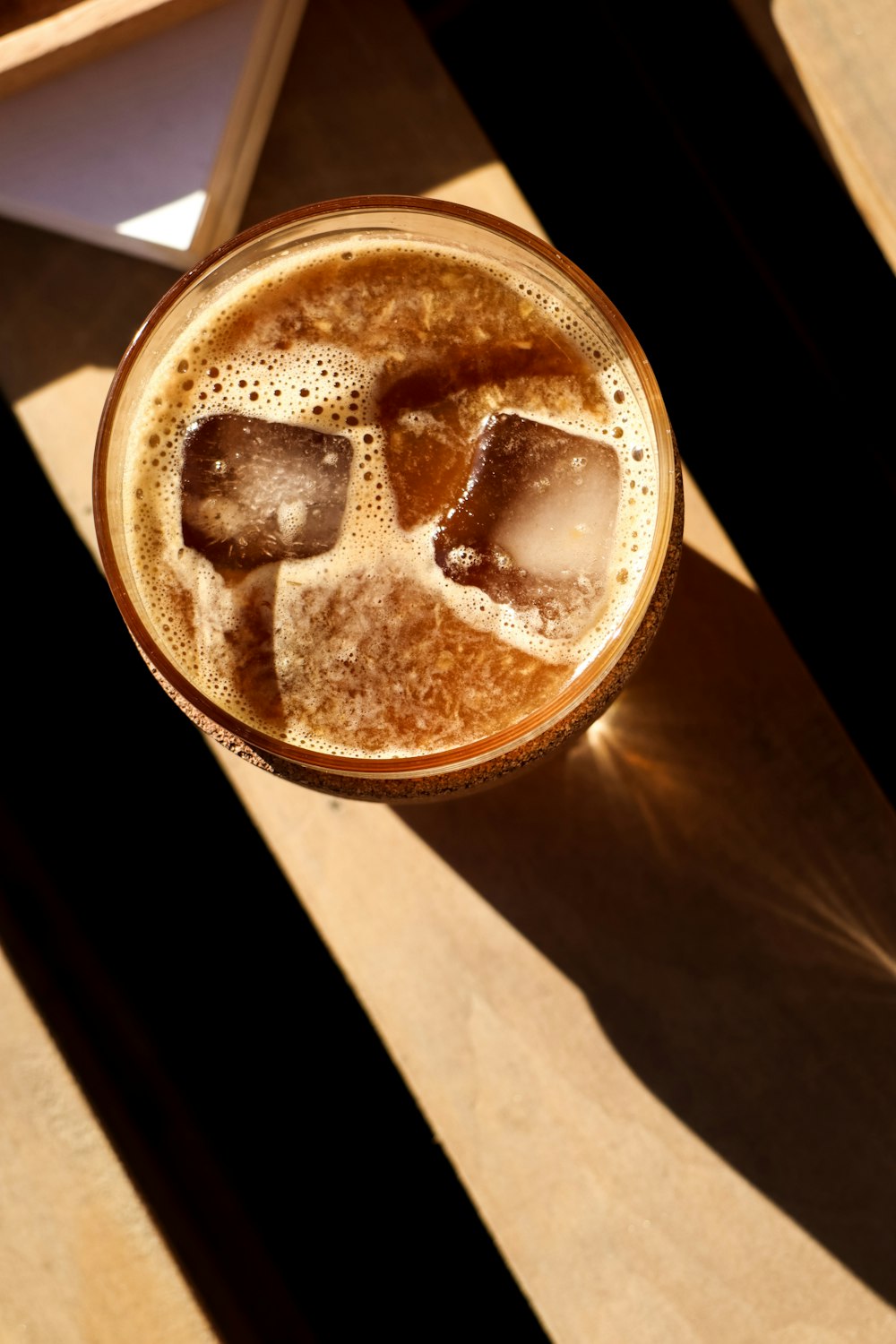 a glass of beer with ice cubes in it