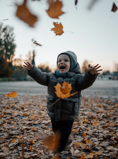 A playful chick exploring colorful autumn leaves near the lodge