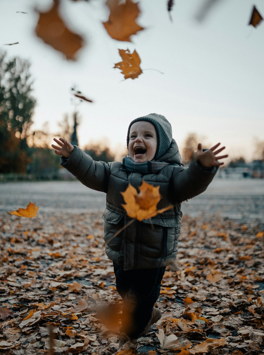 a young boy is playing in the leaves