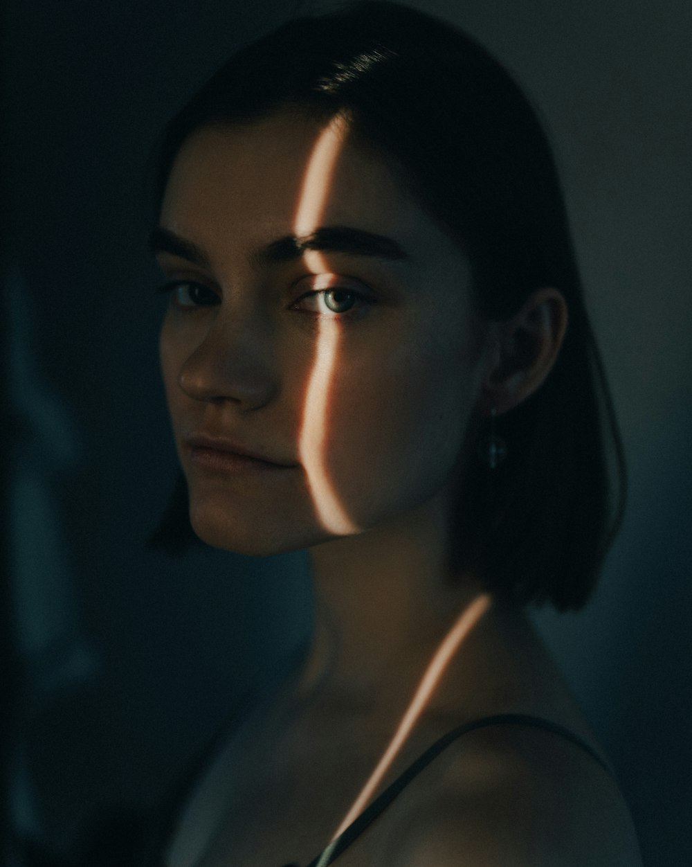 a woman in a dark room with a light shining on her face