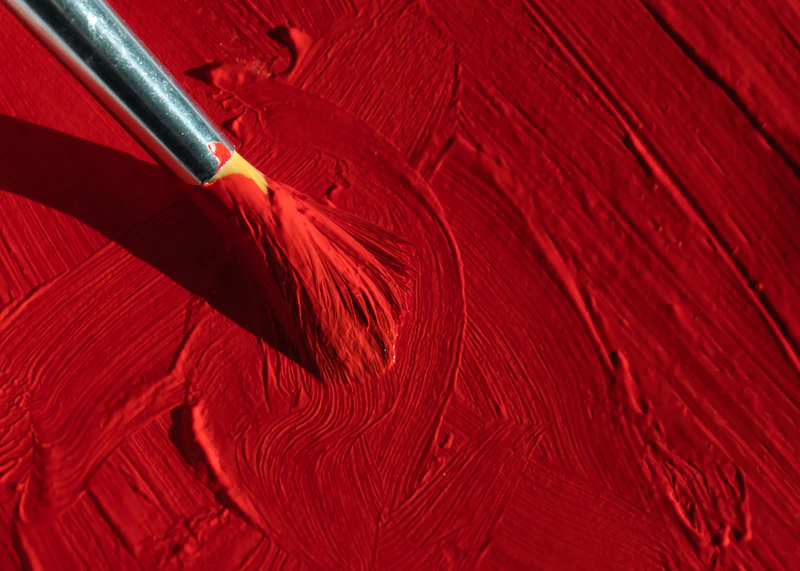 A paintbrush with red paint on canvas