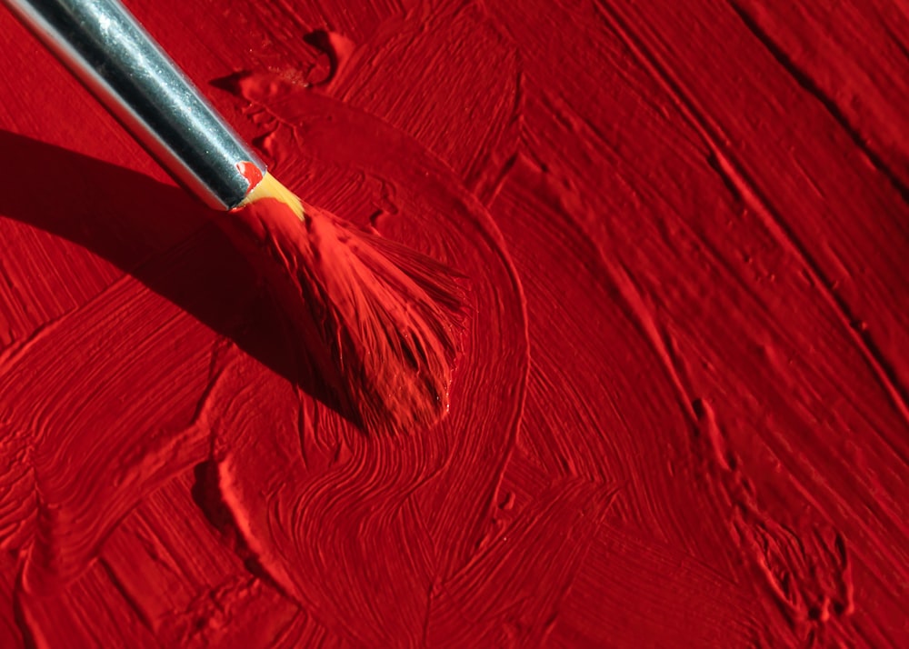 a paint brush is being used to paint a red surface