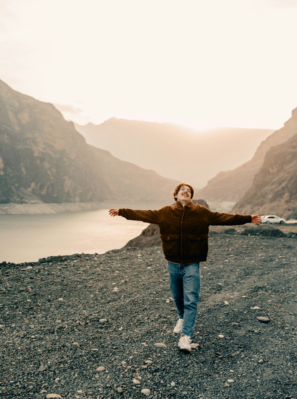 a man standing on top of a mountain next to a lake