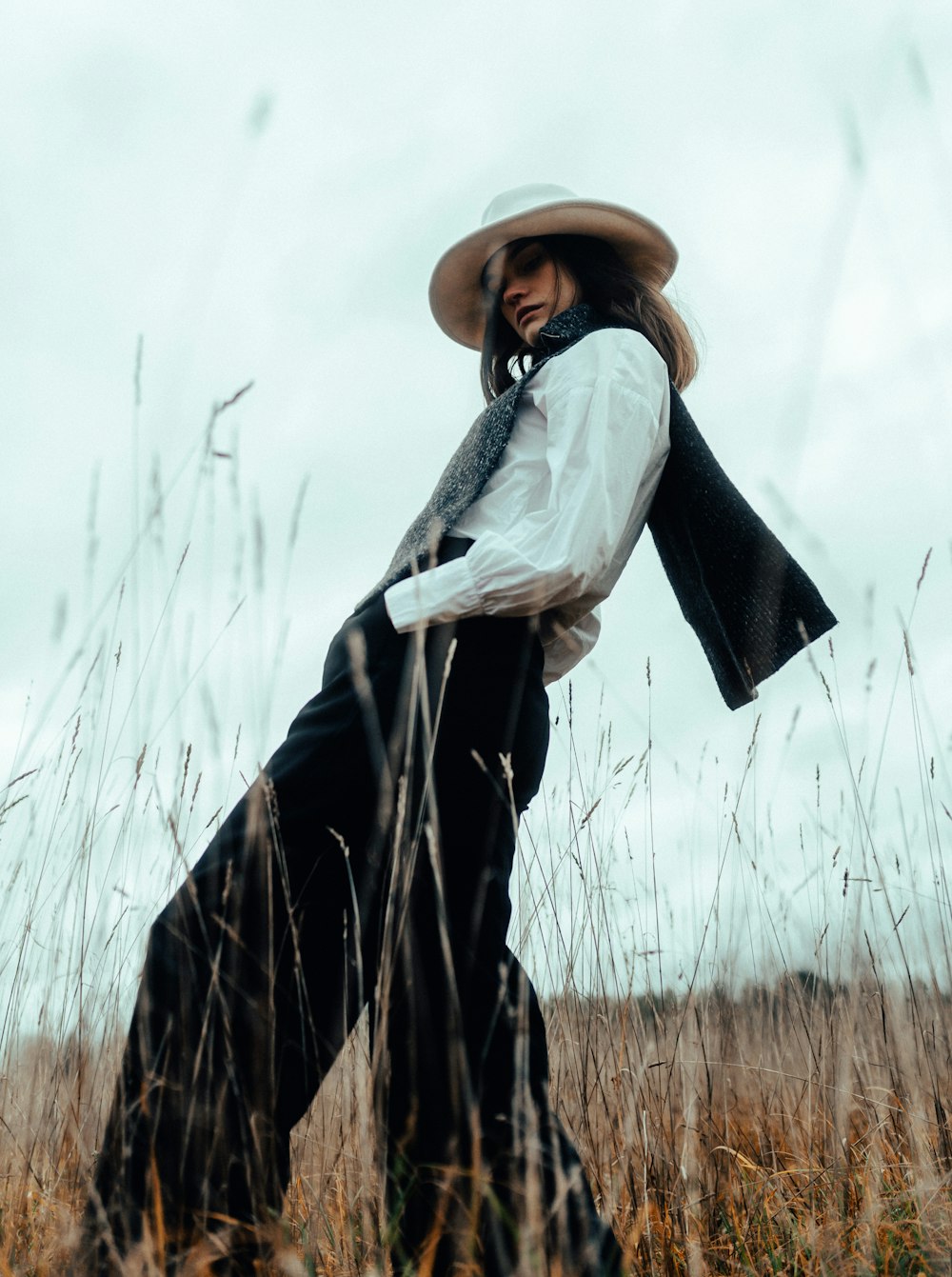 a woman standing in a field with a hat on her head