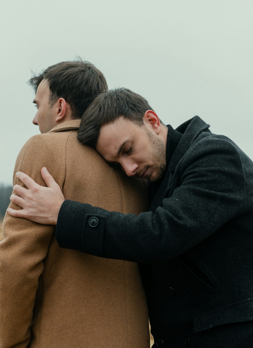a couple of men hugging each other in a field