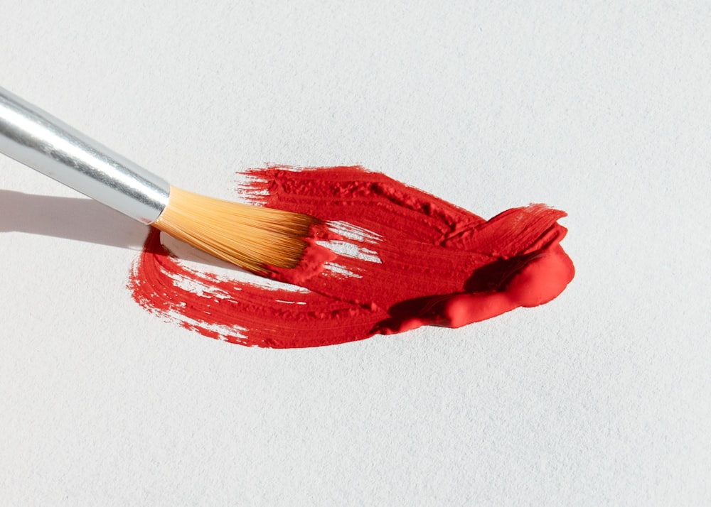 a brush with red paint on a white surface